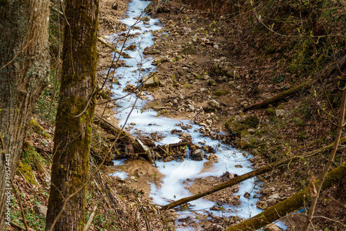 A stream in a ravine of white and blue color, environmental pollution by enterprises, drainage of construction fluid photo