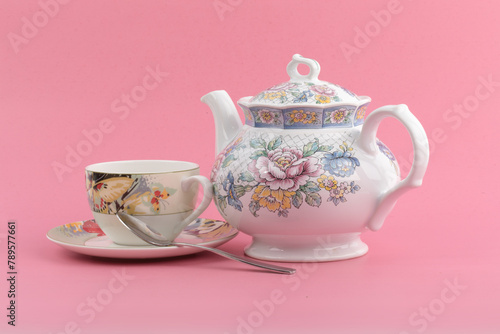 A colorful teapot and teacup on a pink background