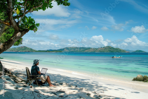 A person working on a laptop at a beach