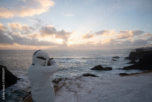 A photographer faces the sea in Iceland before sunset in winter. photo