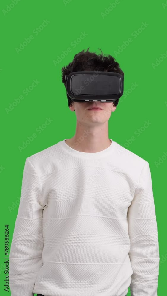 Happy and joyful Caucasian young man using VR headset on chroma key background. Innovation technology, futuristic entertainment. Vertical video. Happy and joyful Caucasian young man using VR headset on chroma key background. Innovation technology, futuristic entertainment. Vertical video.