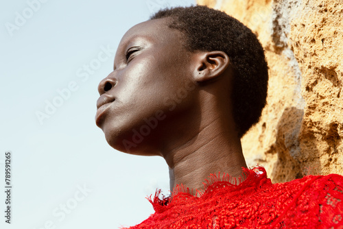 portrait of a young woman of color in a flowing red dress at the beach photo