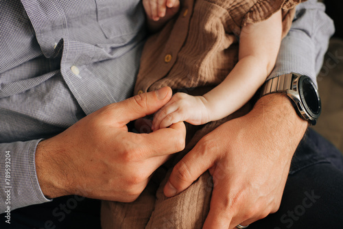 Anonymous father holding hand of his baby daughter