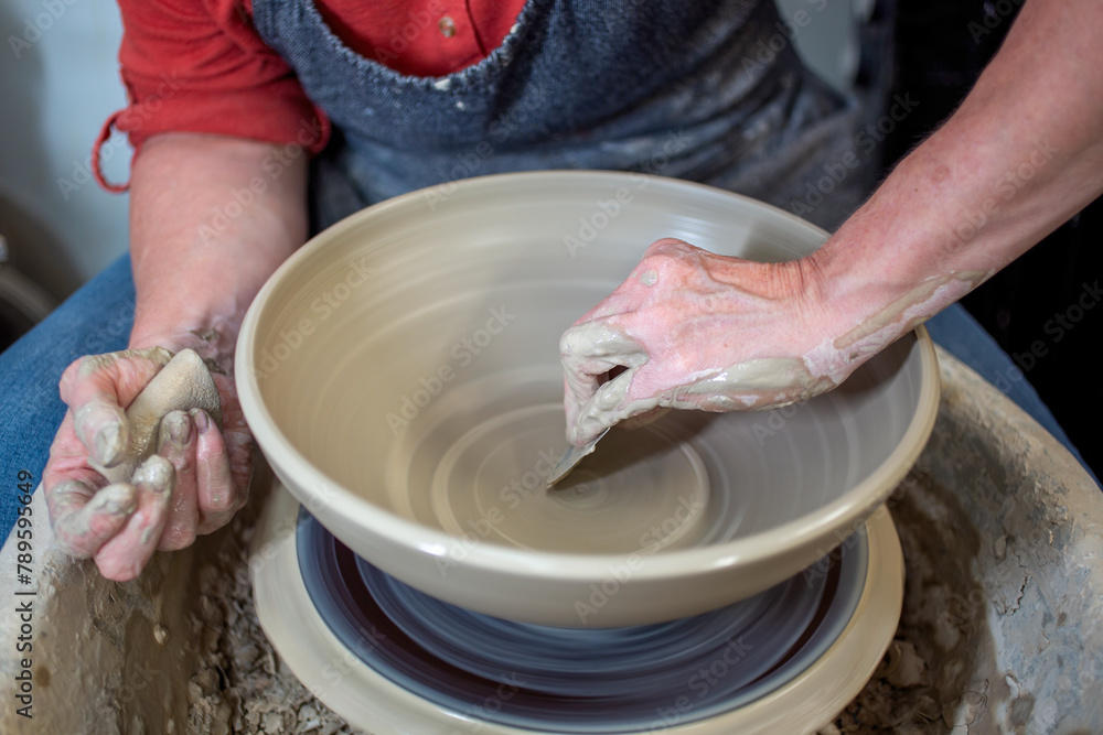 Potter's hands throwing a bowl on a pottery wheel