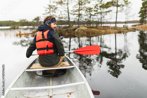 Young man rowing a kayak on a forest Lake photo