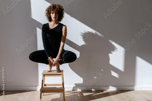 Young woman sitting on wooden stool in room photo