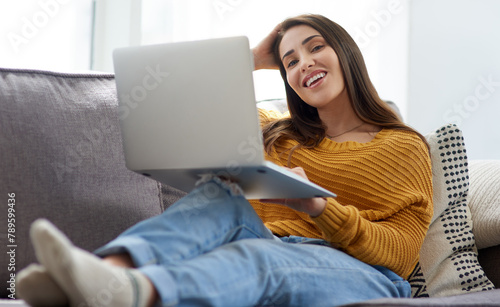 Portrait, laptop and woman on sofa watching funny movie, film or show in living room together. Laughing, happy and female person streaming a comedy video online with computer in lounge at home.