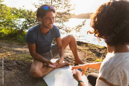 Cheerful friends playing cards in hiking trip during sunset photo