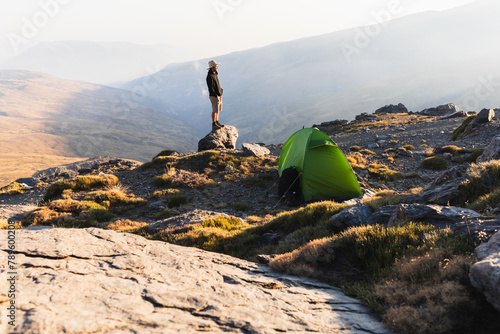 Traveler with tent in mountainous terrain photo