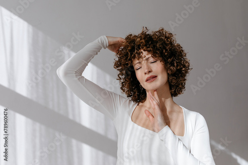 Stylish woman closing eyes and touching hair and chin photo