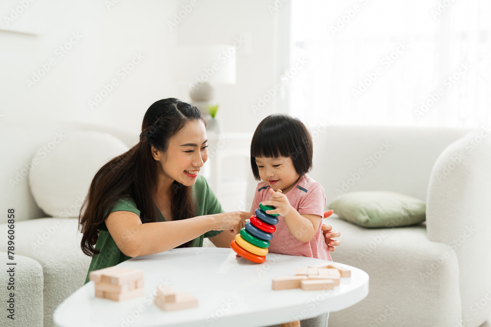 Young mother with her little daughter play game in wood block Young mother with her little daughter play game in wood block