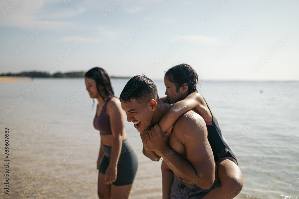 Father giving his daughter piggyback on the beach Father giving his daughter piggyback on the beach