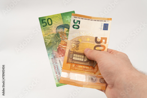 Man holding 50 CHF Swiss franc and 50 EUR Euro banknote paper currency isolated on white background photo