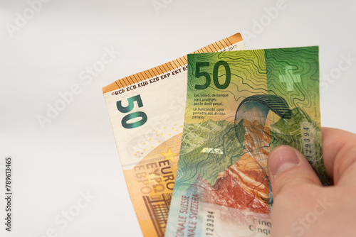 Man holding 50 CHF Swiss franc and 50 EUR Euro banknote paper currency isolated on white background