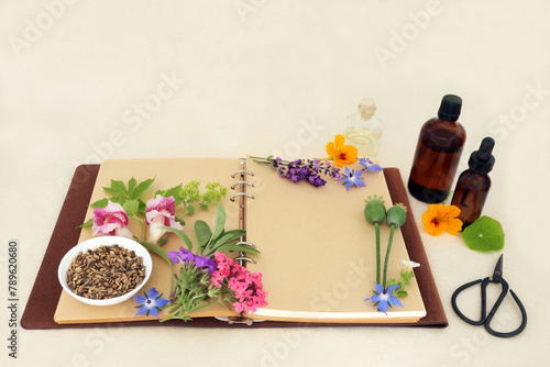 Herbal medicine preparation with flowers and herbs for natural aromatherapy treatments. Ingredients for alternative remedies with recipe notebook, essence bottles on hemp paper.