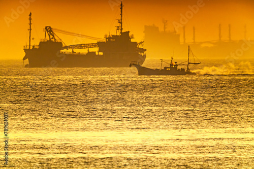 朝日を浴びる海で漁場へ向かう漁船20240414-3 photo