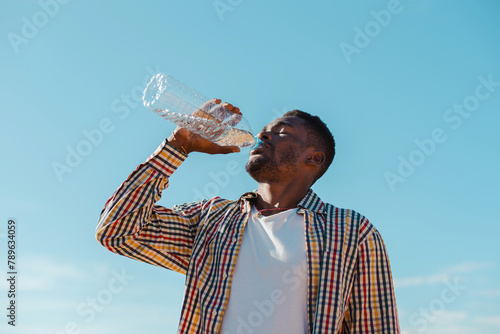 Black man drinking water from a plastic bottle photo