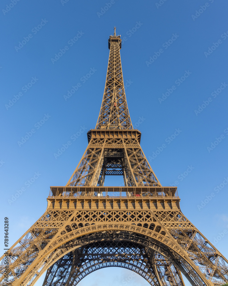 Paris, the Eiffel Tower from below against a blue sky. tall perspective photograph