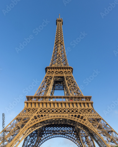 Paris, the Eiffel Tower from below against a blue sky. tall perspective photograph