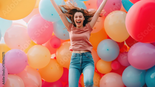 A woman joyfully jumps in the air surrounded by colorful balloons in a clear blue sky