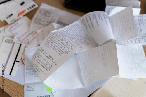 Messy workplace desk with utility bills, tax forms, invoices, receipts photo