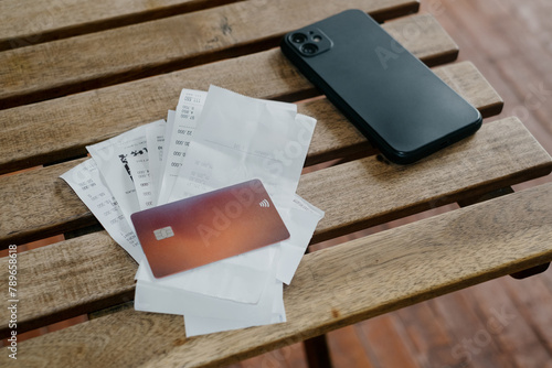 Bunch or receipts on the table with card and smartphone photo