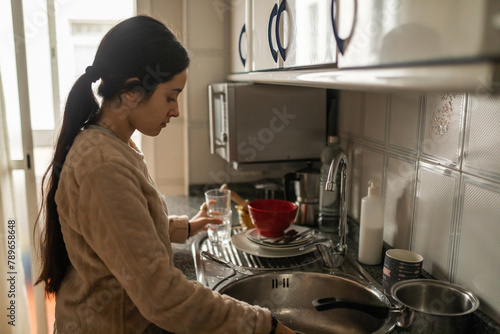 teenage girl in pajamas washing dishes in the kitchen photo
