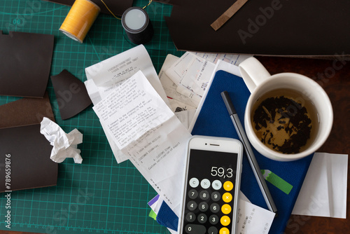 Creative workspace of leatherworker filled with receipts and tools. photo