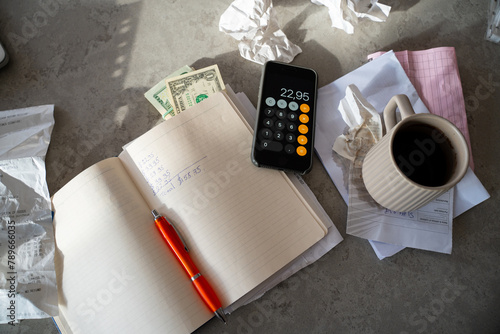 Messy workspace: phone calculator, notebook, cash money, receipts