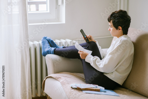 Young woman pays heating bill with smartphone