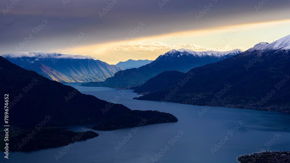 Sun beams light the mountains over Como lake