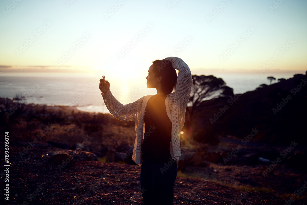 Obraz premium Hiking, selfie and woman on mountain at sunset with nature evening sky and relax on holiday adventure. Digital photography, outdoor trekking and person with natural view, ocean and memory on vacation
