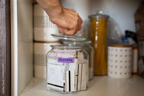 UGC, an unrecognizable male hand putting receipts into a glass jar photo