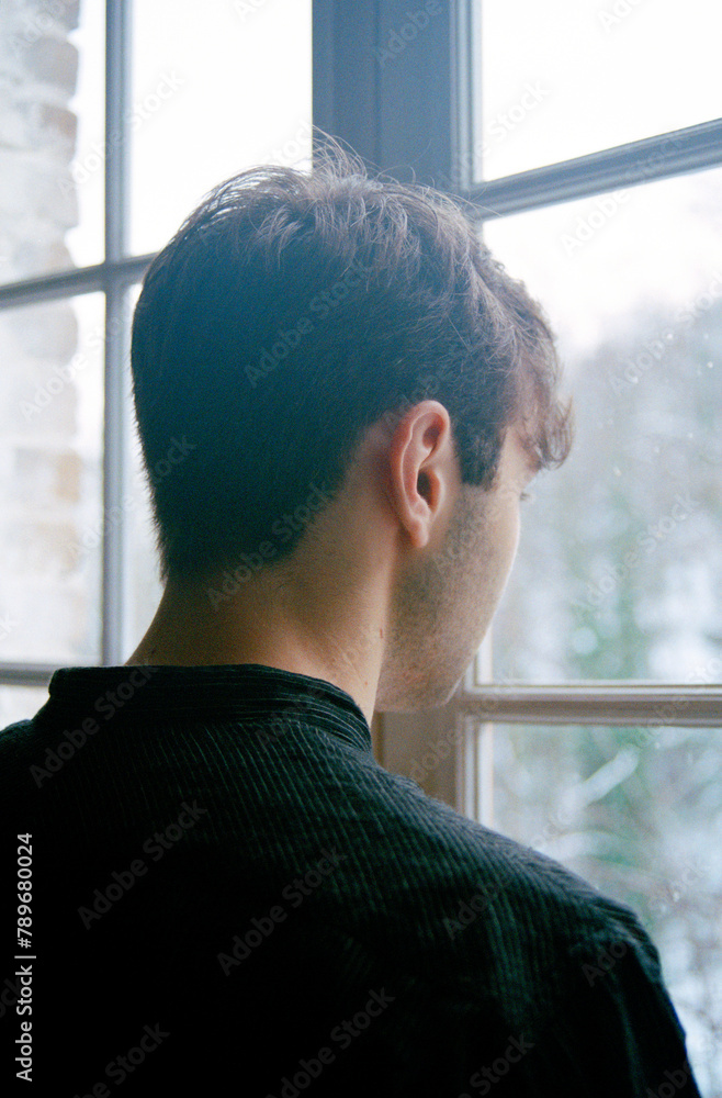 Analog portrait of a young man by the window Analog portrait of a young man by the window