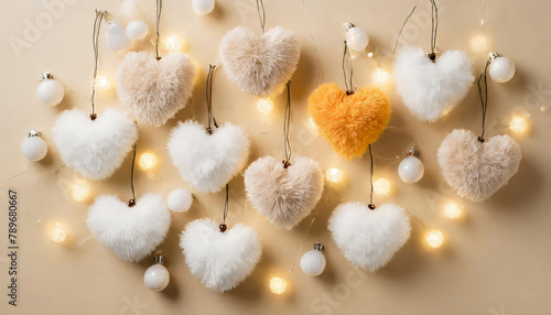 Top view photo of soft heart shaped toy light bulb garland and fluffy pompons on isolated pastel beige background with copyspace photo