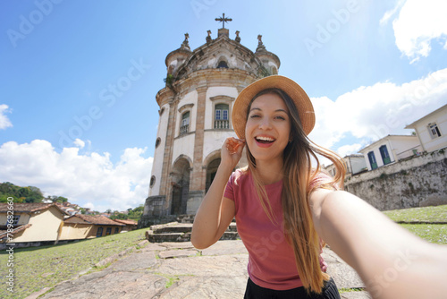 Selfie girl in Ouro Preto, Brazil. Young tourist woman taking self portrait with the church of Our Lady of the Rosary in Ouro Preto touristic destination UNESCO in Minas Gerais, Brazil.