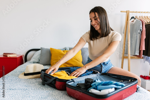 Young happy woman preparing suitcase for summer vacation trip. Travel and holidays concept. © Xavier Lorenzo