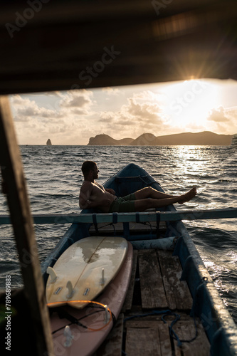 Surfer Reclining on Boat, Summer Vives Golden Hour in Indonesia photo