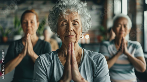 A group of elderly women are participating in a yoga session together, performing various poses and stretches in a studio setting photo