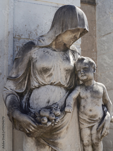 Estatua tallada en mármol de Carrara de mujer con niño en brazos, representando amor y protección photo