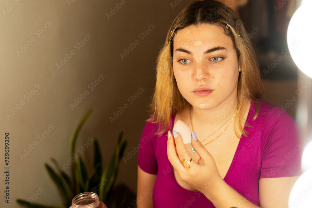 teenager girl applying concealer with a beauty blender teenager girl applying concealer with a beauty blender