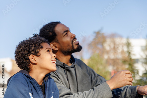 Smiling father and son looking up while having leisure time together