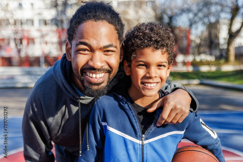 Portrait of smiling father and son on basketball court 