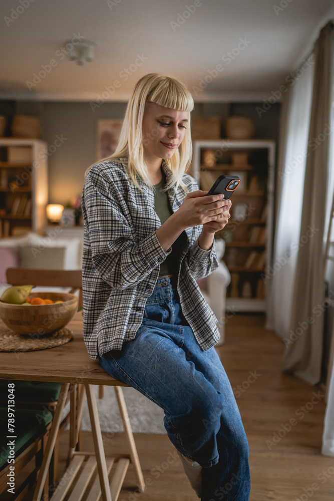 © Miljan Živković - Young woman text message and browse internet on mobile phone at home
