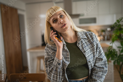 Young woman talk on mobile phone and think about something at home