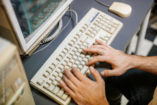 Hands on the keys of a vintage computer keyboard from the 90s photo