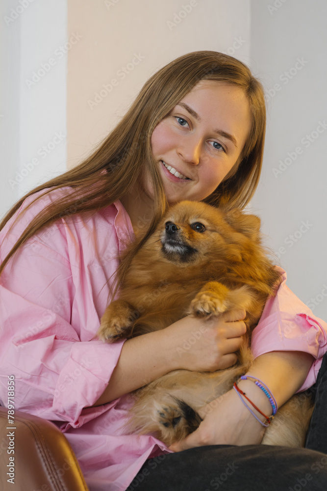 Smiling woman hugging cute Pomeranian dog in room Smiling woman hugging cute Pomeranian dog in room