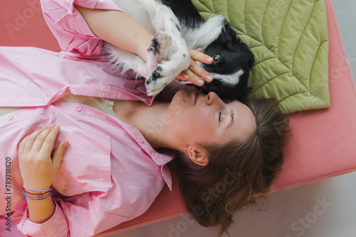 Happy woman with adorable dog lying on pink floor