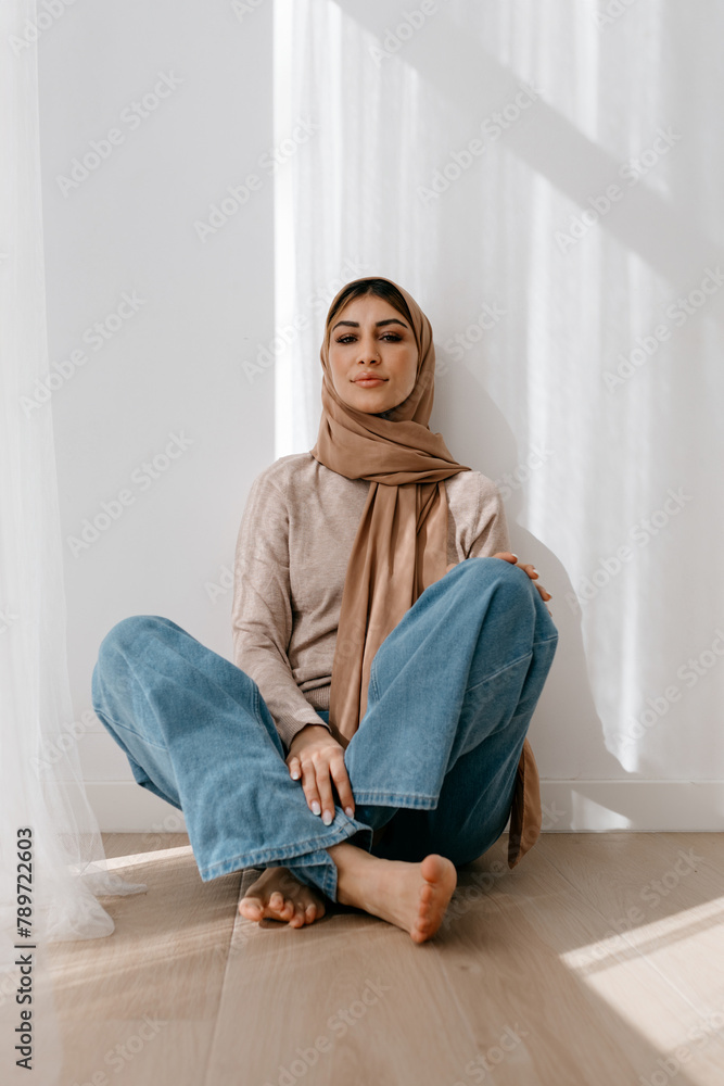 Muslim woman sitting on floor in studio Muslim woman sitting on floor in studio