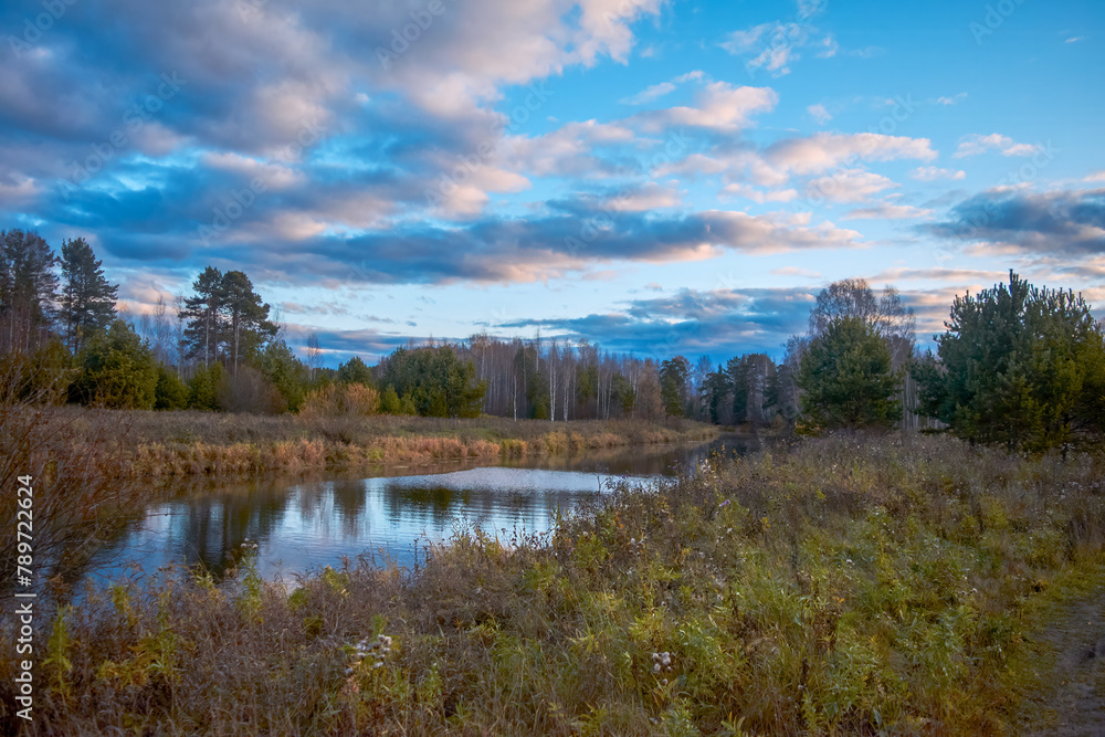 Autumn landscape with riverbank at sunset. Wonderful nature, beautiful natural background. Sky with clouds is reflected in the water. Autumn landscape with riverbank at sunset. Wonderful nature, beautiful natural background. Sky with clouds is reflected in the water.